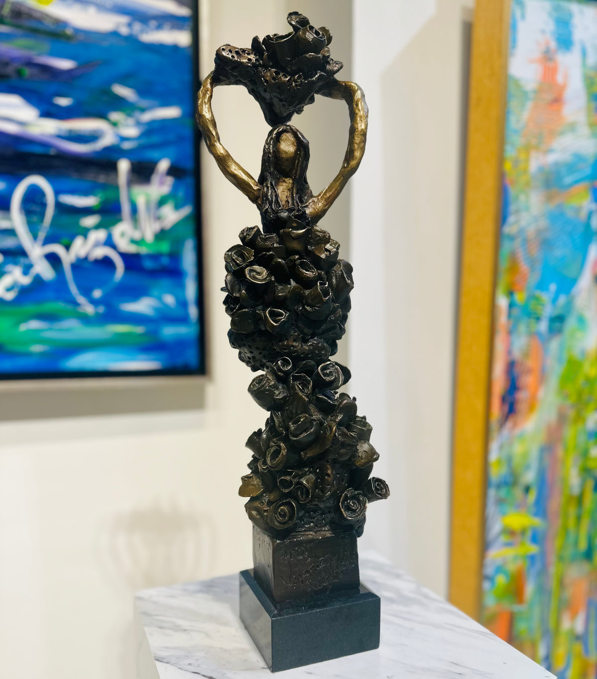 Ashleigh Adeline — bronze sculpture by Veronica Ruiz de Velasco. A dark bronze figure rises from a base of clustered rose-like forms, gilt arms lifted to frame a heart.