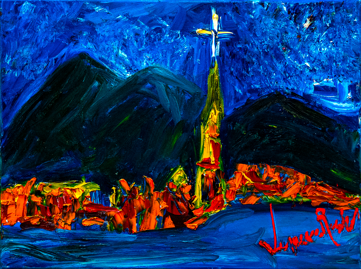 Austria — by Veronica Ruiz de Velasco: a night scene of dark mountains and a steeple with a glowing white cross above orange rooftops under a cobalt sky